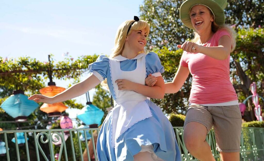 Adult earing mad hatter's top hat, skipping along with Alice in Wonderland
