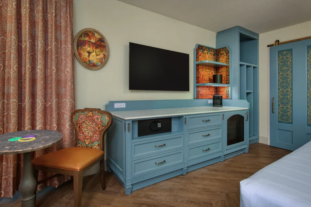 Port Orleans room from the entry displaying refurbished Dresser with light colors and a small table an chairs with decor evoking the style of New Orleans.