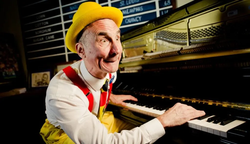 Piano player in bold colors with suspenders making fun face